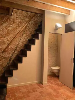a staircase in a room with a toilet and a brick wall at Idyllische, historische woning op het hippe zuid in Antwerp