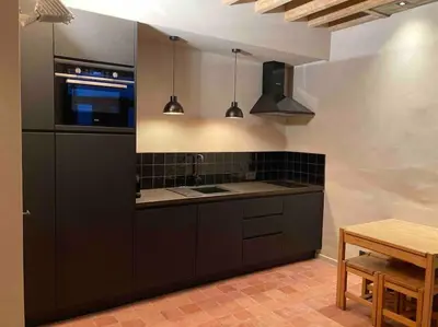 a kitchen with black cabinets and a table in it at Idyllische, historische woning op het hippe zuid in Antwerp