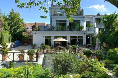 a large white house with a patio with an umbrella at 1000m2 villa with indoor pool in Brussels