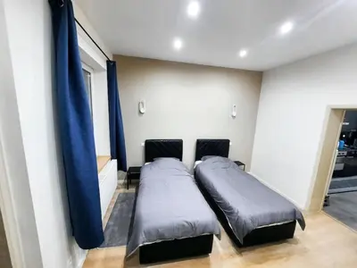 two beds in a room with blue curtains at Modern Apartment in Molenbeek-Saint-Jean / 77 m² / Parking in Brussels