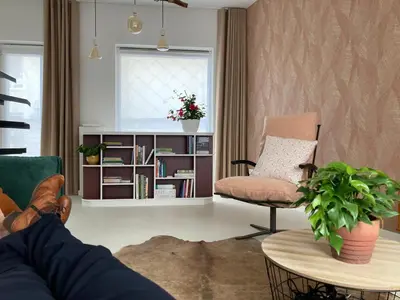 a living room with a chair and a book shelf at Charmante stadswoning aan Groen Kwartier in Antwerp