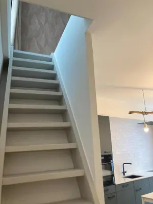 a staircase in a kitchen with white walls at Charmante stadswoning aan Groen Kwartier in Antwerp