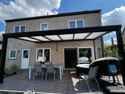 a patio with a white pergola in front of a house at Tommorowland in Niel