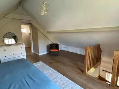 an attic bedroom with a bed and a dresser and a chair at Duplex Rosières - 12’ de Bruxelles in Rixensart