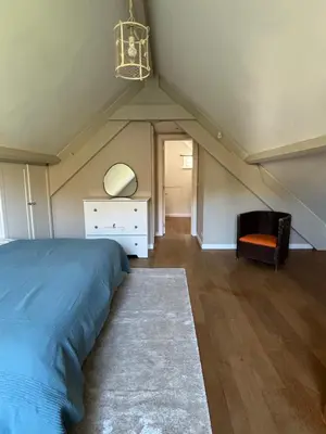 a bedroom with a bed and a dresser and a chair at Duplex Rosières - 12’ de Bruxelles in Rixensart