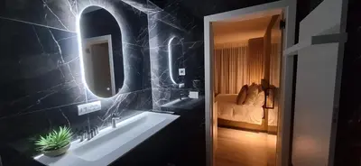 a bathroom with a sink and a mirror and a bed at Den Ommegang in Halle