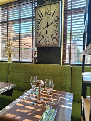 a table with wine glasses and a clock in a restaurant at Den Ommegang in Halle
