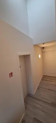 an empty room with a white ceiling and wooden floors at Den Ommegang in Halle