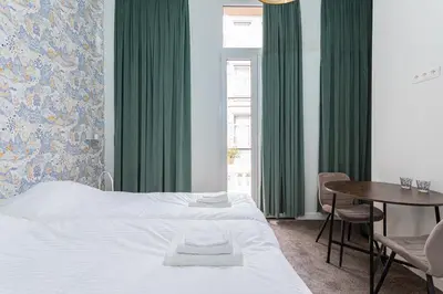 a bedroom with a bed and a table and green curtains at Room6 Van Lerius in Antwerp