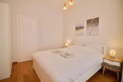 a bedroom with a white bed with two candles on it at Heart of Grand Place - Stunning 3BR Triplex in Brussels