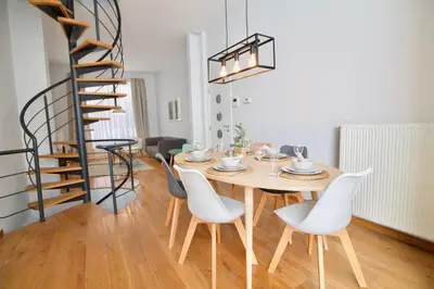 a dining room with a table and chairs and a spiral staircase at Heart of Grand Place - Stunning 3BR Triplex in Brussels