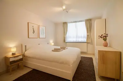 a bedroom with a white bed and a window at Heart of Grand Place - Stunning 3BR Triplex in Brussels