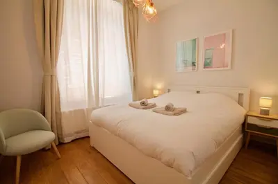 a bedroom with a bed and a chair and a window at Heart of Grand Place - Stunning 3BR Triplex in Brussels