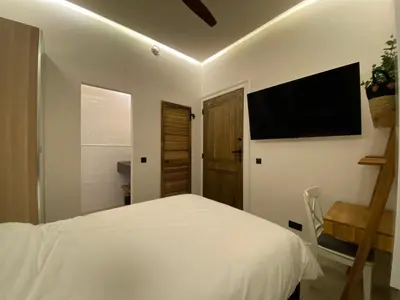 a bedroom with a white bed and a flat screen tv at Roxy's Fishmarket in Leuven