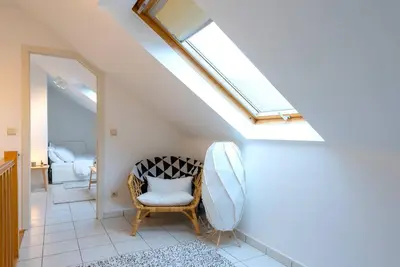 a room with a skylight and a chair with a pillow at Jette Expo Duplex Residence in Brussels