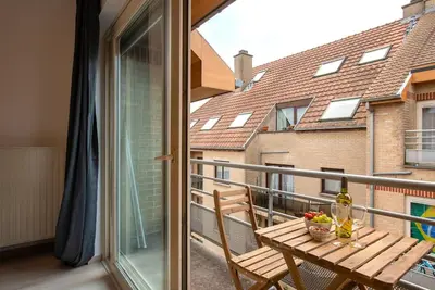 a balcony with a wooden table and a window at Jette Expo Duplex Residence in Brussels
