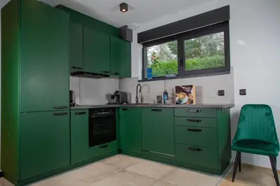 a green kitchen with green cabinets and a window at Meerbeek Unwind in Kortenberg