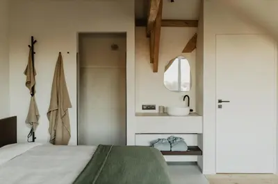 a bedroom with a bed and a bathroom with a sink at Stil 1827 in Sint-Laureins