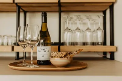a bottle of wine and a bowl of cheese and wine glasses at Stil 1827 in Sint-Laureins