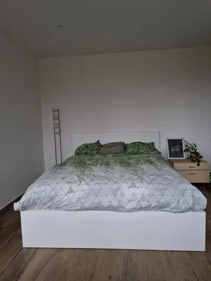 a white bed in a room with a white wall at Volledige gezinswoning te huur in Mechelen
