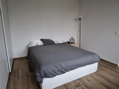 a bedroom with a bed in a white room at Volledige gezinswoning te huur in Mechelen