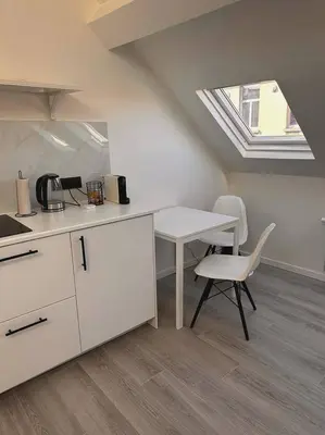 a white kitchen with a table and a chair at Skyroof à Ixelles - Viaduc in Brussels