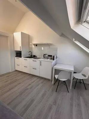 a kitchen with white cabinets and a table and chairs at Skyroof à Ixelles - Viaduc in Brussels