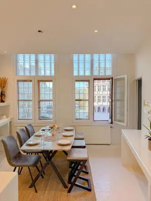 a dining room with a table and chairs and windows at Le FauBourg Suites in Antwerp