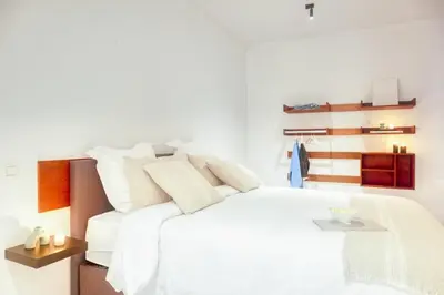 a white bedroom with a white bed and wooden shelves at Wonderful 6P duplex in Antwerp in Antwerp