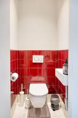 a red tiled bathroom with a white toilet in it at Wonderful 6P duplex in Antwerp in Antwerp