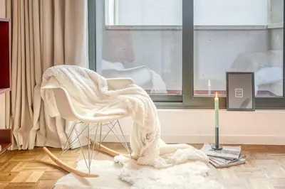 a blanket on a chair in a room with a candle at Smart and cosy 4P Apt in Antwerp with balcony in Antwerp