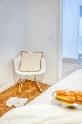a white chair sitting next to a bed with a plate of food at Ample 2-BR Apt in Antwerp in Antwerp