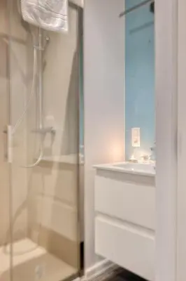 a shower with a glass door next to a sink at Ample 2-BR Apt in Antwerp in Antwerp