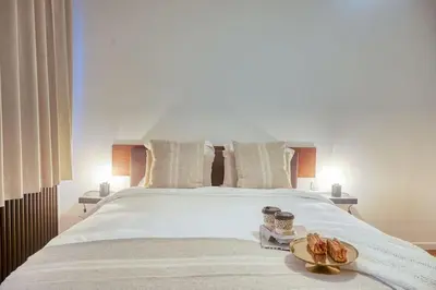 a large white bed with two plates of food on it at Ample 2-BR Apt in Antwerp in Antwerp