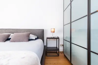 a bedroom with a bed and a side table with a lamp at Le Havre de Lumière à Etterbeek in Brussels