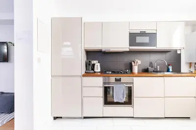 a white kitchen with white cabinets and appliances at Le Havre de Lumière à Etterbeek in Brussels