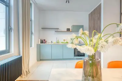a vase with flowers on a table in a kitchen at 2-BR Haven in Antwerp in Antwerp