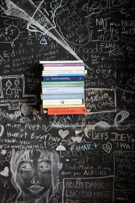 a stack of books on a wall with chalk writings at B'Kanal in Brussels