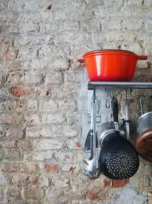 a pot and a spatula hanging on a brick wall at B'Kanal in Brussels