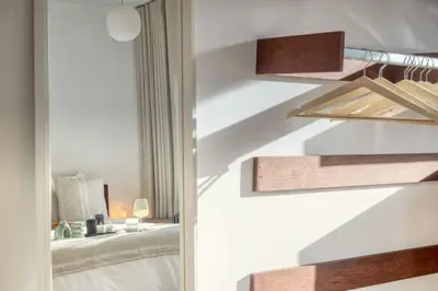 a bedroom with white walls and a staircase with a bed at Cozy Retreat in Antwerp with balcony in Antwerp