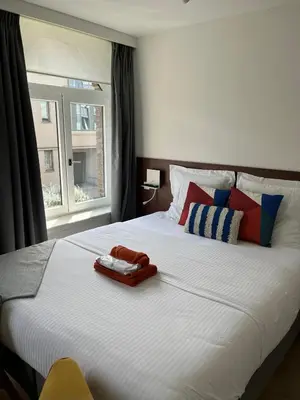 a bedroom with a large white bed with a window at Business Accommodation 'Eclectic Living' Nomad in Geel