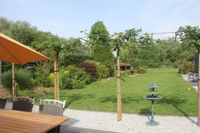 a garden with a table and a bird feeder at B&B Het KoeKoeKsnest Schelle in Schelle