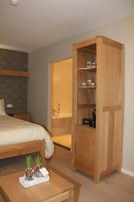a bedroom with a bed and a wooden cabinet at B&B Het KoeKoeKsnest Schelle in Schelle