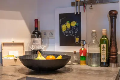 a bowl of fruit sitting on a counter with wine bottles at St Catherine Duplex Residence in Brussels
