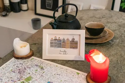 a table with a candle and a picture and a cup of coffee at St Catherine Duplex Residence in Brussels
