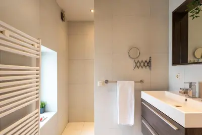 a white bathroom with a sink and a mirror at St Catherine Duplex Residence in Brussels