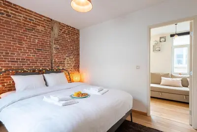 a bedroom with a white bed with a brick wall at St Catherine Duplex Residence in Brussels