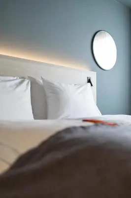 a bedroom with a bed with white pillows and a mirror at Citybox Brussels Centre Louise in Brussels