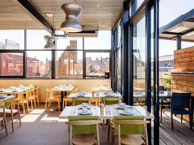 a restaurant with tables and chairs and large windows at Budget Rooms by Ghent River in Ghent