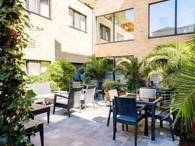 a patio with chairs and tables in front of a building at Budget Rooms by Ghent River in Ghent